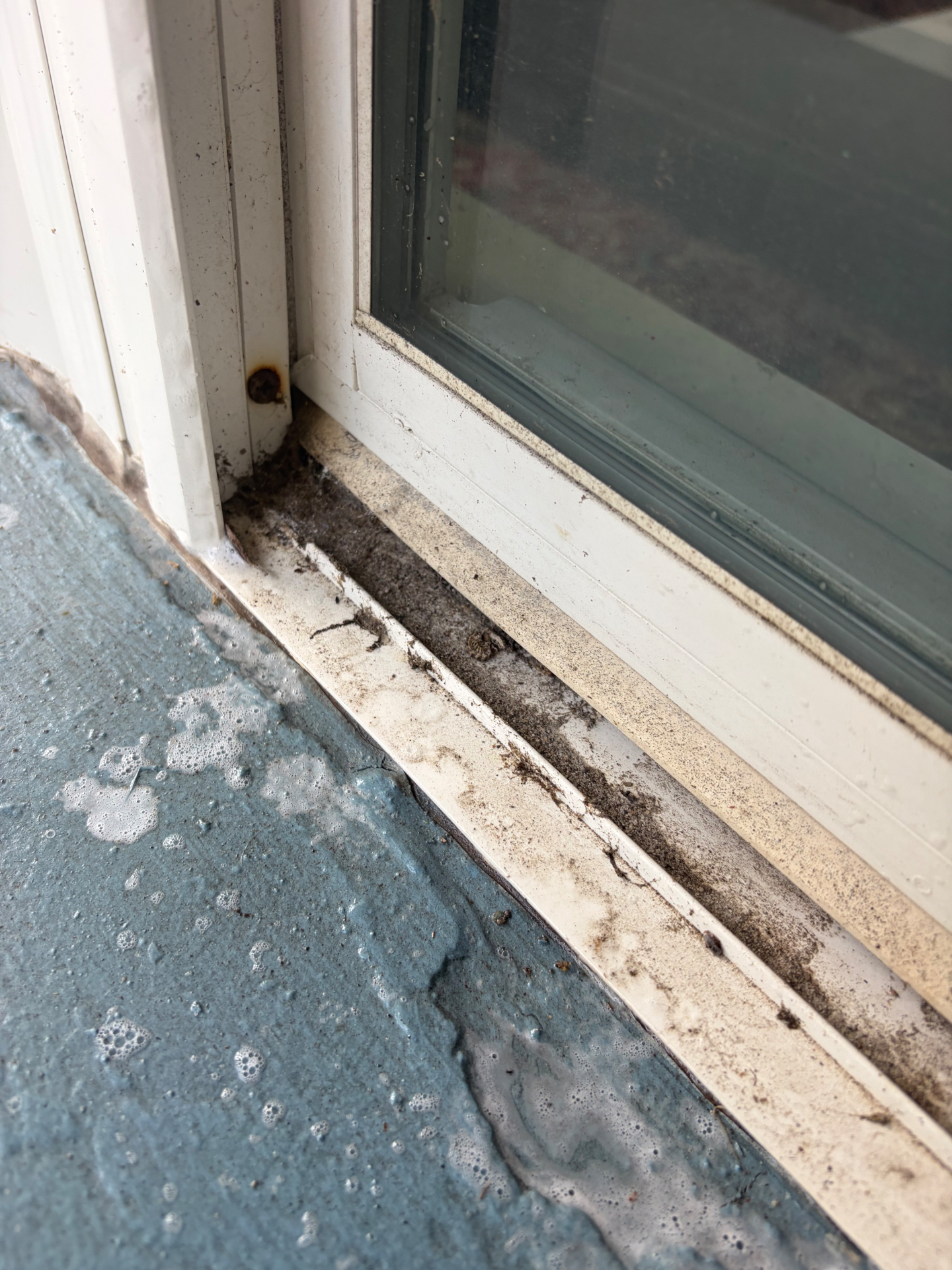 Before: lower slider track filled with sand on a Navarre home